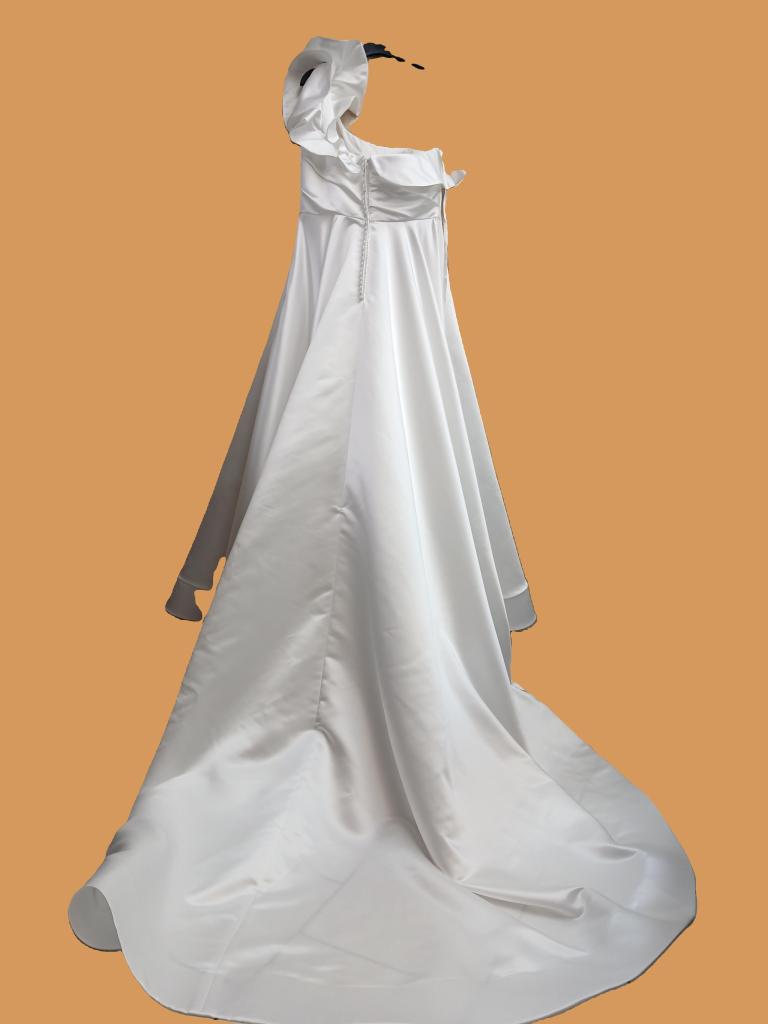 A elegant white dress on a mannequin with a flowing skirt and a ruffled neckline, set against a plain orange background.